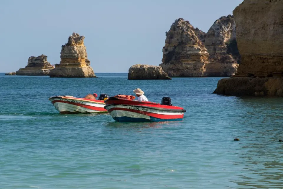 Fishermen in small motor boats near a rocky coast
